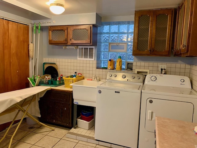 clothes washing area featuring washer and clothes dryer, cabinets, light tile patterned floors, and sink