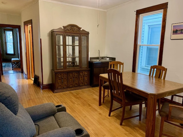 dining area with crown molding, sink, and light hardwood / wood-style flooring