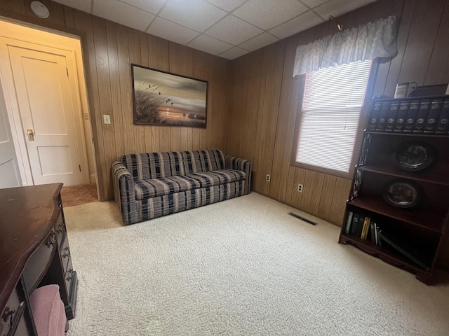 carpeted living room with wood walls