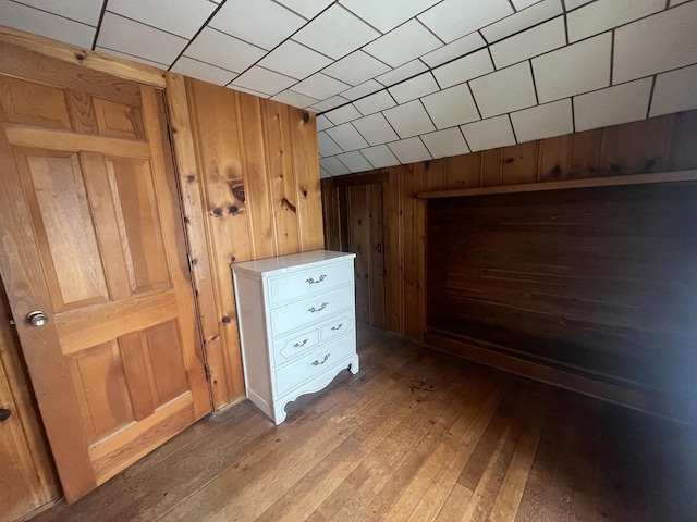 additional living space with hardwood / wood-style floors and wooden walls