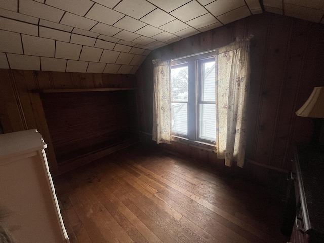 additional living space featuring dark hardwood / wood-style flooring, lofted ceiling, and wooden walls