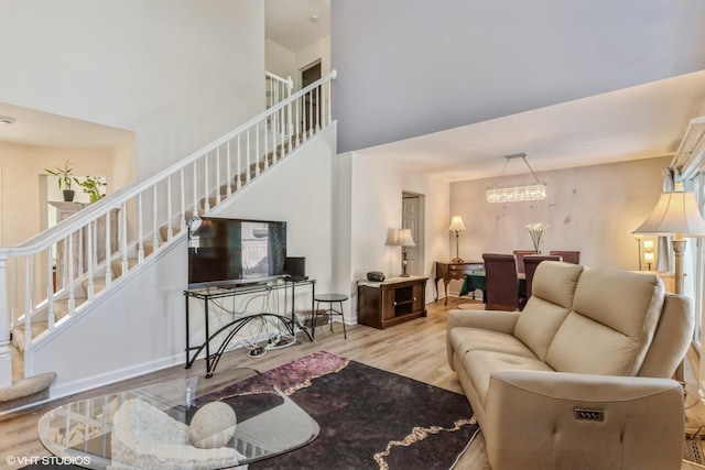 living area with a high ceiling, stairway, and light wood-style flooring