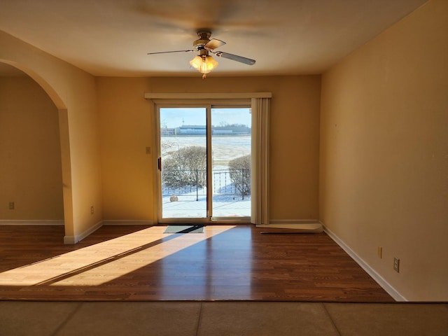 spare room with dark hardwood / wood-style flooring, a water view, and ceiling fan