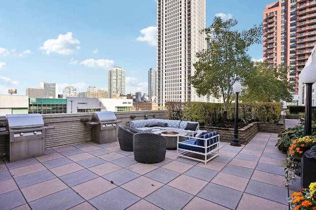 view of patio featuring grilling area, an outdoor living space with a fire pit, and an outdoor kitchen