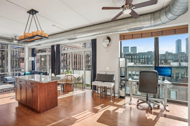 office featuring light wood-type flooring, expansive windows, and ceiling fan