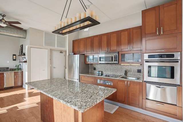 kitchen featuring backsplash, sink, ceiling fan, appliances with stainless steel finishes, and a kitchen island