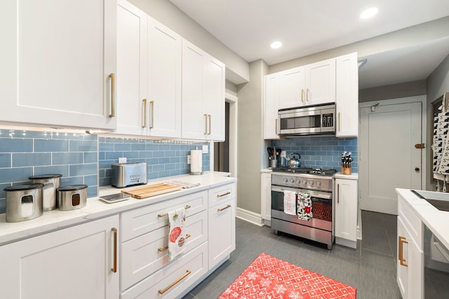 kitchen featuring backsplash, white cabinetry, stainless steel appliances, and dark tile patterned flooring