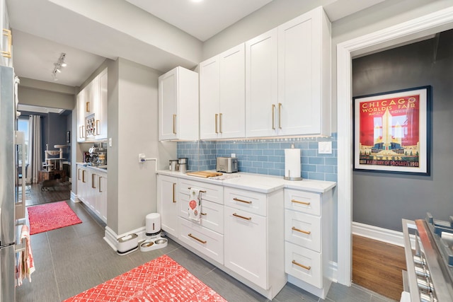 kitchen featuring dark tile patterned flooring, white cabinetry, and tasteful backsplash