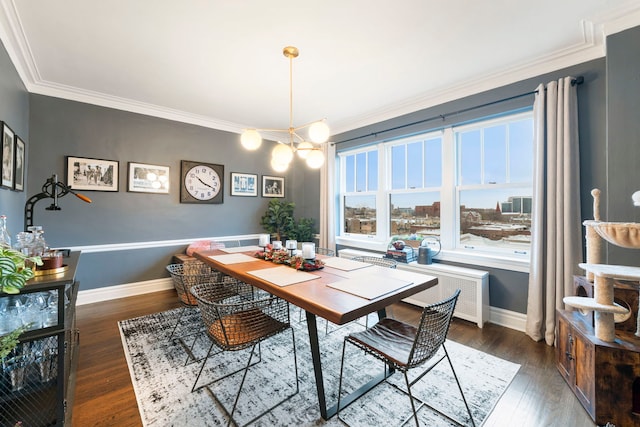 dining area with radiator, crown molding, dark wood-type flooring, and an inviting chandelier