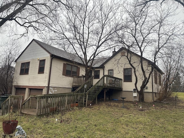 rear view of house with a garage, a wooden deck, and a lawn