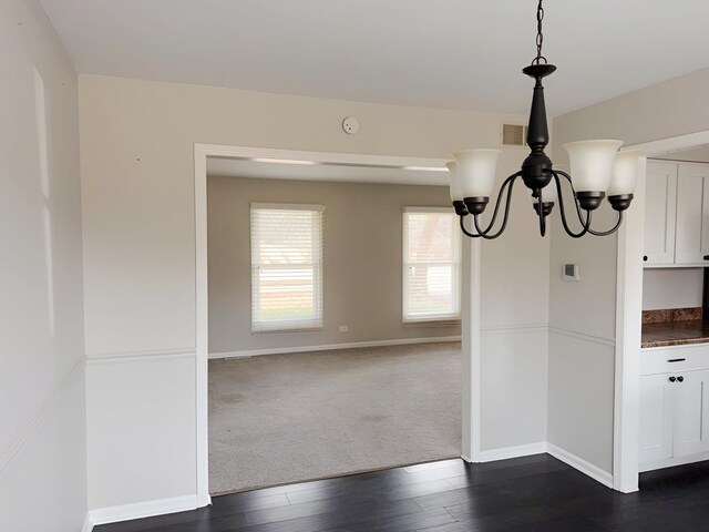 6111 Pingree Rd, Crystal Lake, IL 60014 - unfurnished dining area featuring a chandelier, dark wood-style flooring, baseboards, and dark colored carpet
