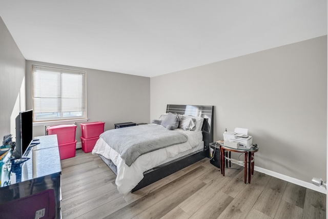 bedroom featuring a baseboard heating unit and light hardwood / wood-style flooring