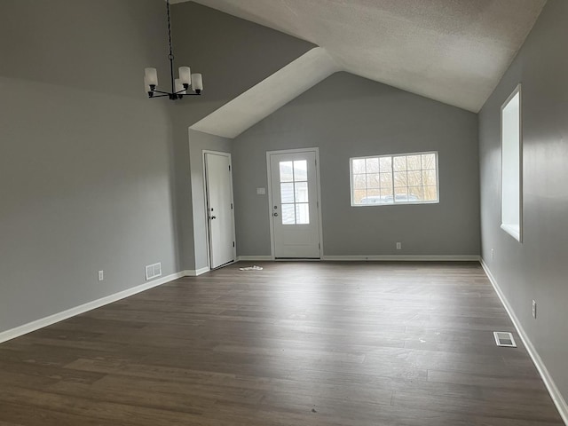 interior space featuring dark hardwood / wood-style floors, vaulted ceiling, a textured ceiling, and a chandelier