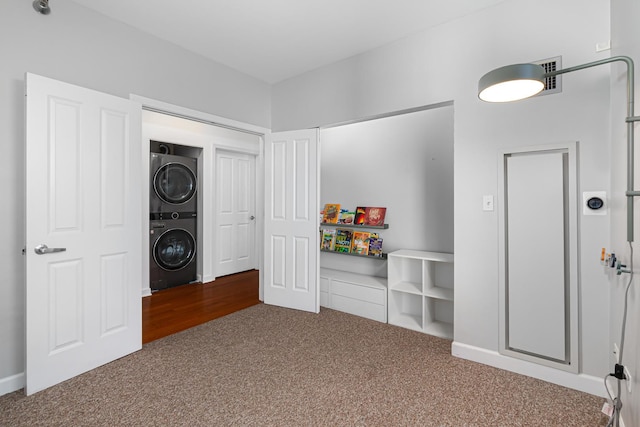 interior space with carpet flooring and stacked washer and clothes dryer