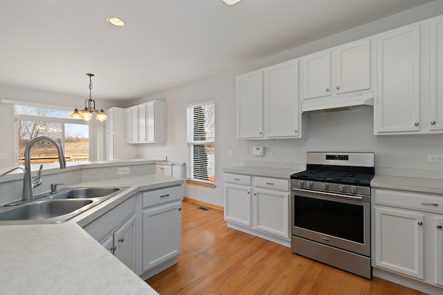 kitchen with pendant lighting, white cabinetry, stainless steel gas range oven, and sink