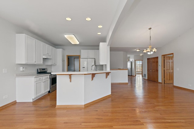 kitchen featuring a kitchen island with sink, white cabinets, hanging light fixtures, a notable chandelier, and stainless steel range oven