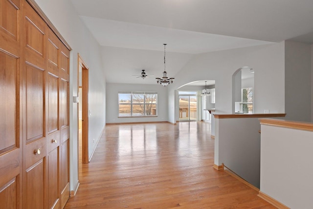 hall featuring light hardwood / wood-style floors, vaulted ceiling, and a notable chandelier