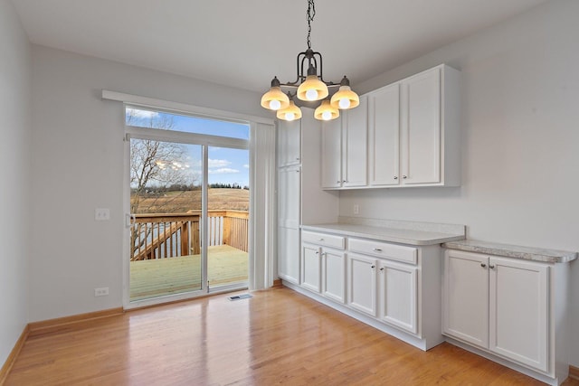 unfurnished dining area with light wood-type flooring and an inviting chandelier