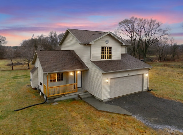 view of front of home with covered porch, a yard, and a garage