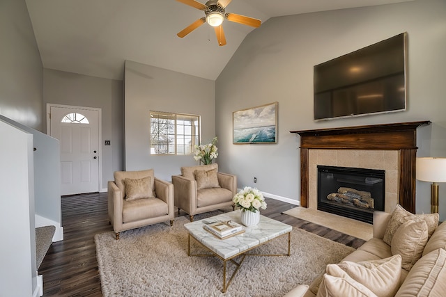 living room featuring dark hardwood / wood-style floors, ceiling fan, lofted ceiling, and a tiled fireplace