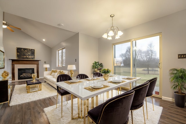 dining room featuring ceiling fan with notable chandelier, dark hardwood / wood-style flooring, and vaulted ceiling