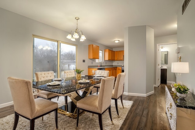 dining space featuring dark hardwood / wood-style flooring, sink, and a chandelier