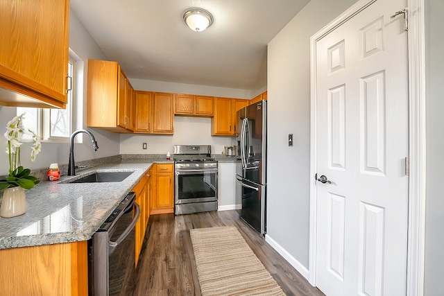 kitchen featuring light stone countertops, sink, stainless steel appliances, and dark hardwood / wood-style floors