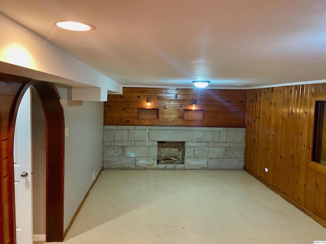 unfurnished living room with a fireplace and wood walls