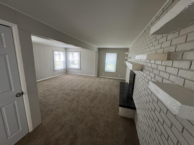 unfurnished living room featuring carpet flooring and brick wall