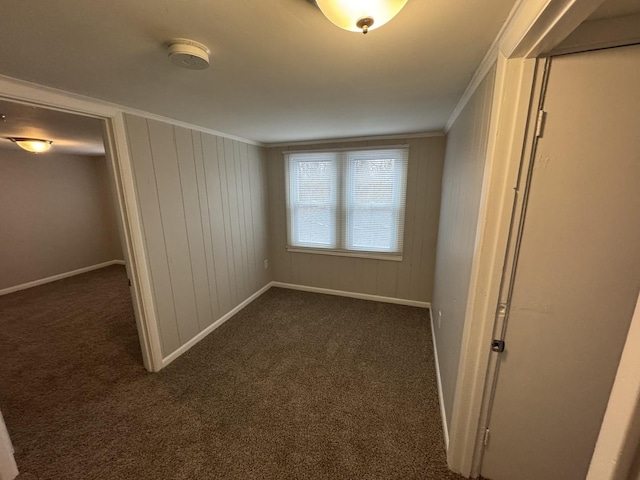 unfurnished bedroom featuring wooden walls, dark carpet, and crown molding