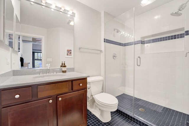 bathroom featuring tile patterned floors, vanity, toilet, and a shower with door