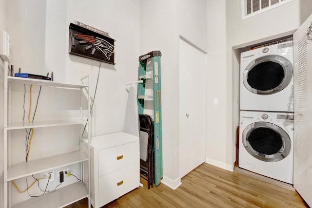 washroom with hardwood / wood-style floors and stacked washer / drying machine