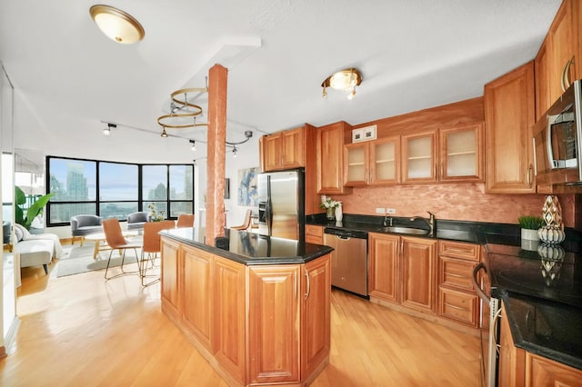 kitchen featuring sink, a center island, stainless steel appliances, backsplash, and light hardwood / wood-style floors