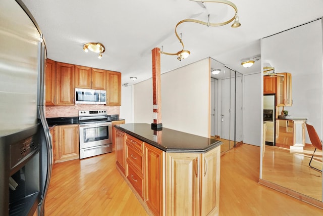 kitchen with backsplash, a center island, stainless steel appliances, and light hardwood / wood-style flooring