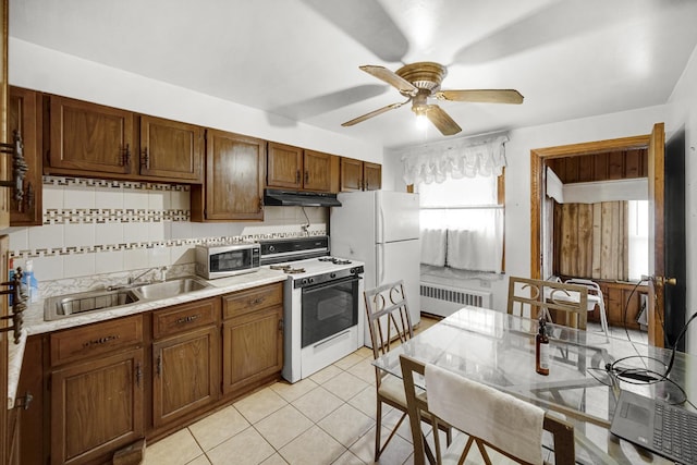 kitchen with white appliances, radiator, sink, ceiling fan, and decorative backsplash