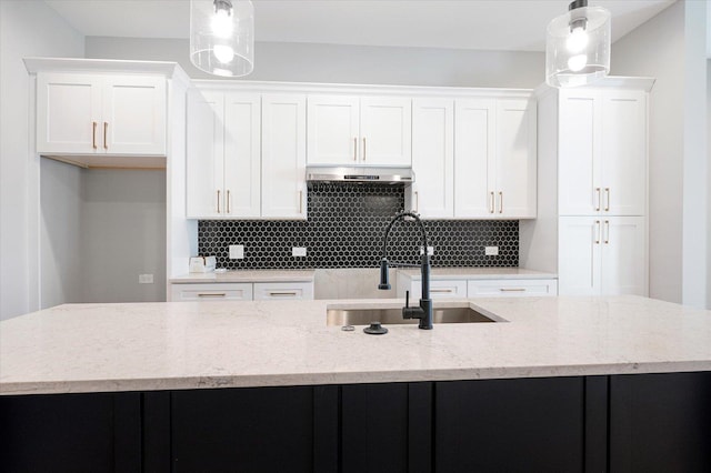 kitchen with decorative light fixtures, white cabinetry, and a kitchen island with sink