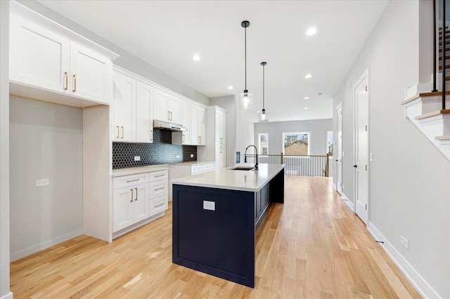 kitchen featuring pendant lighting, sink, white cabinets, and a kitchen island with sink