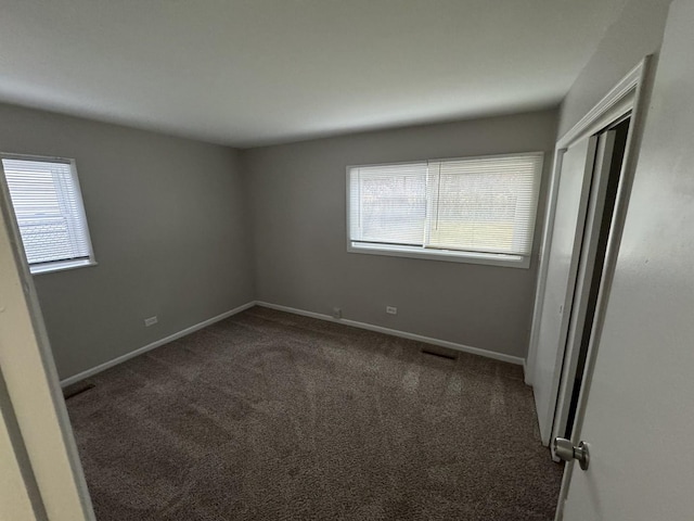 spare room with dark colored carpet