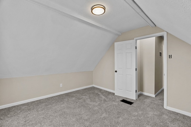 bonus room featuring lofted ceiling, light colored carpet, and a textured ceiling