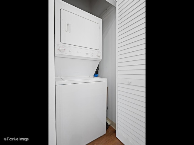 laundry room with hardwood / wood-style floors and stacked washing maching and dryer