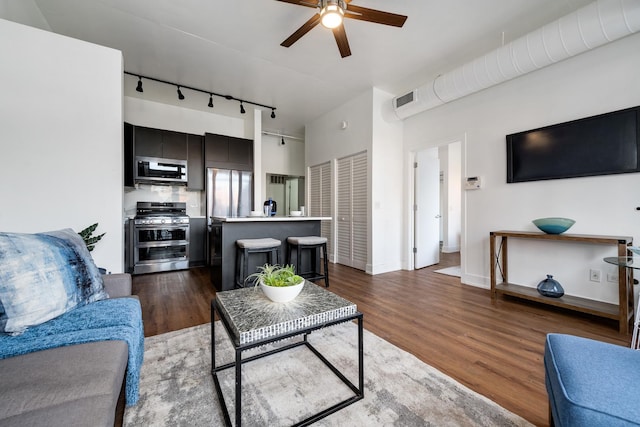 living room with dark hardwood / wood-style floors, ceiling fan, and rail lighting