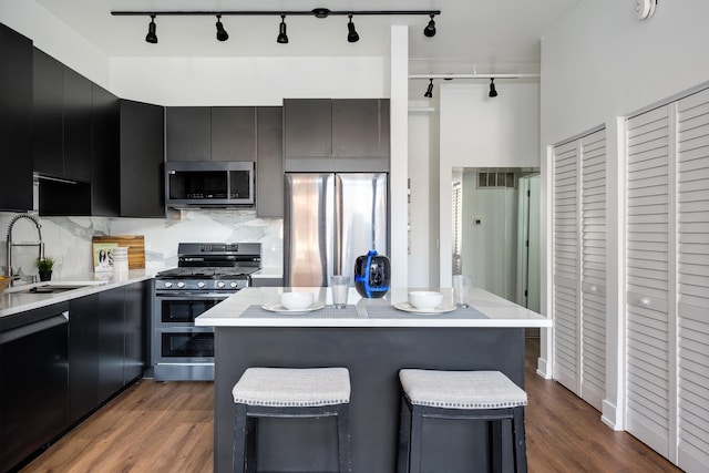 kitchen featuring sink, a kitchen breakfast bar, tasteful backsplash, dark hardwood / wood-style floors, and appliances with stainless steel finishes