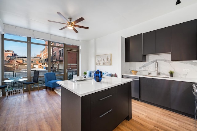 kitchen with dishwasher, sink, tasteful backsplash, light hardwood / wood-style flooring, and a kitchen island