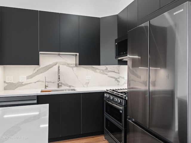 kitchen with tasteful backsplash, sink, light hardwood / wood-style flooring, and appliances with stainless steel finishes