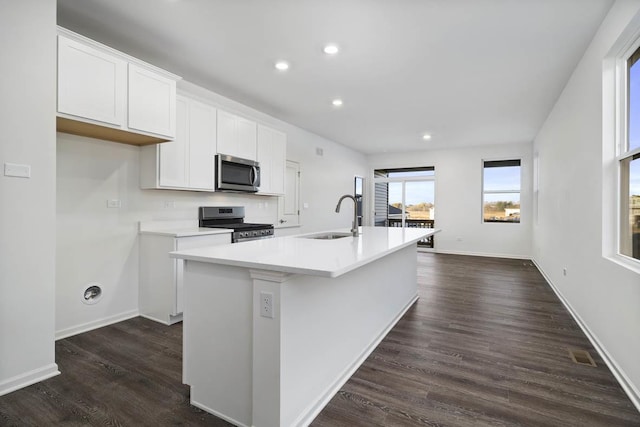 kitchen with a kitchen island with sink, sink, dark hardwood / wood-style floors, appliances with stainless steel finishes, and white cabinetry