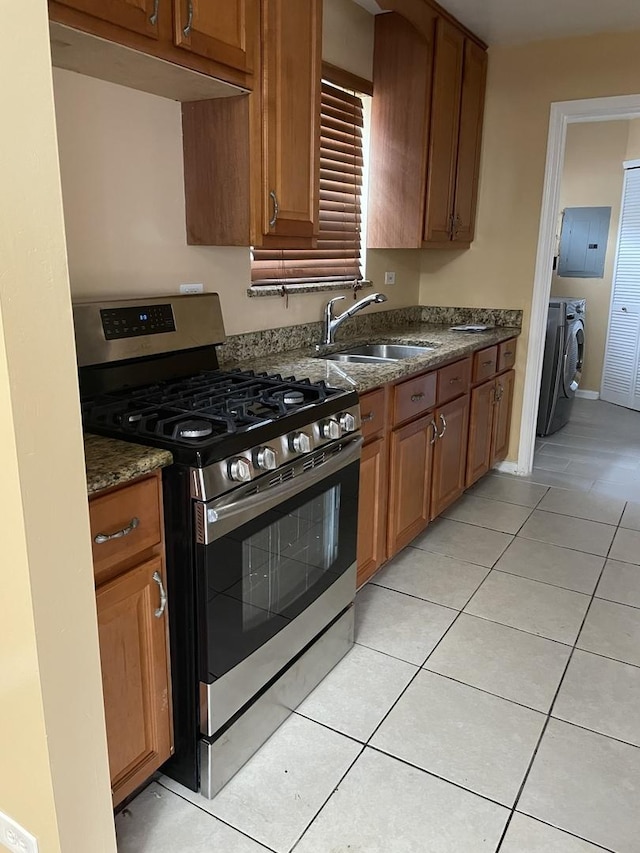 kitchen featuring sink, stainless steel gas range oven, separate washer and dryer, electric panel, and light tile patterned flooring