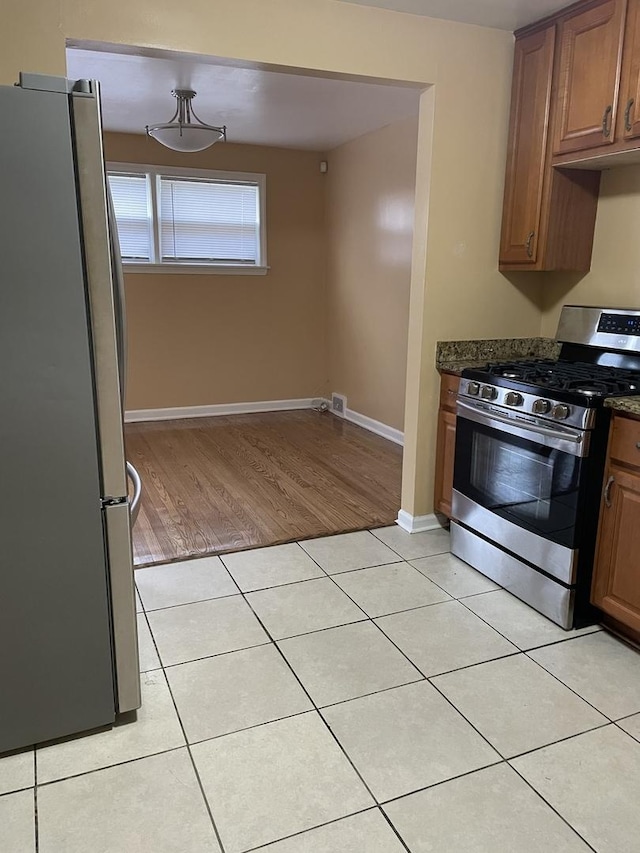 kitchen with light tile patterned floors, stainless steel appliances, and dark stone counters