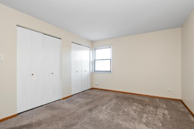 unfurnished bedroom with carpet flooring and two closets