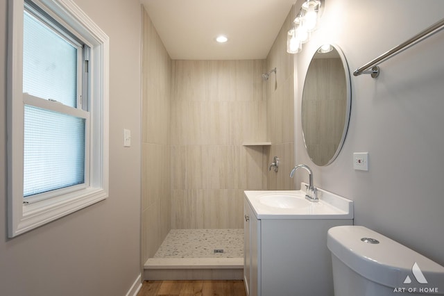 bathroom featuring a tile shower, vanity, and toilet