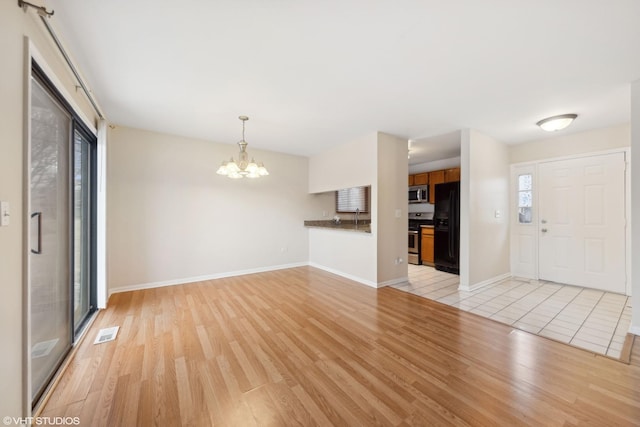 unfurnished living room with a notable chandelier and light hardwood / wood-style floors